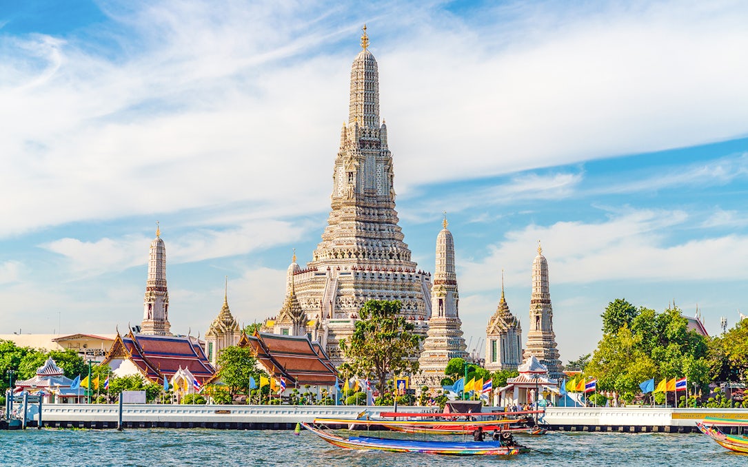 Wat Arun temple with colorful boats on Chao Phraya River, Bangkok, Thailand.