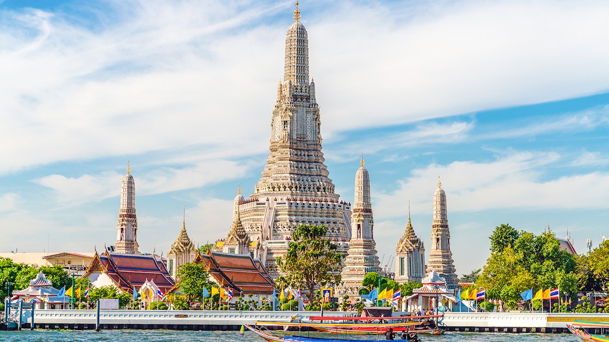 Wat Arun temple with colorful boats on Chao Phraya River, Bangkok, Thailand.