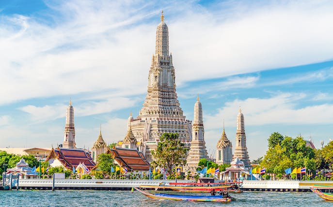 Wat Arun temple with colorful boats on Chao Phraya River, Bangkok, Thailand.