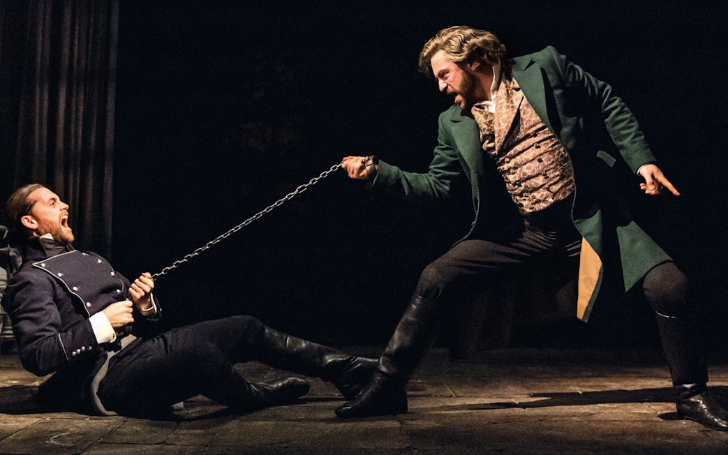 Actors performing a dramatic scene from Les Miserables on stage.