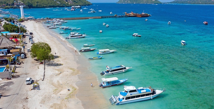 Boats anchored at Toya Pakeh Harbour, Nusa Penida, Bali, Indonesia, with clear turquoise waters.