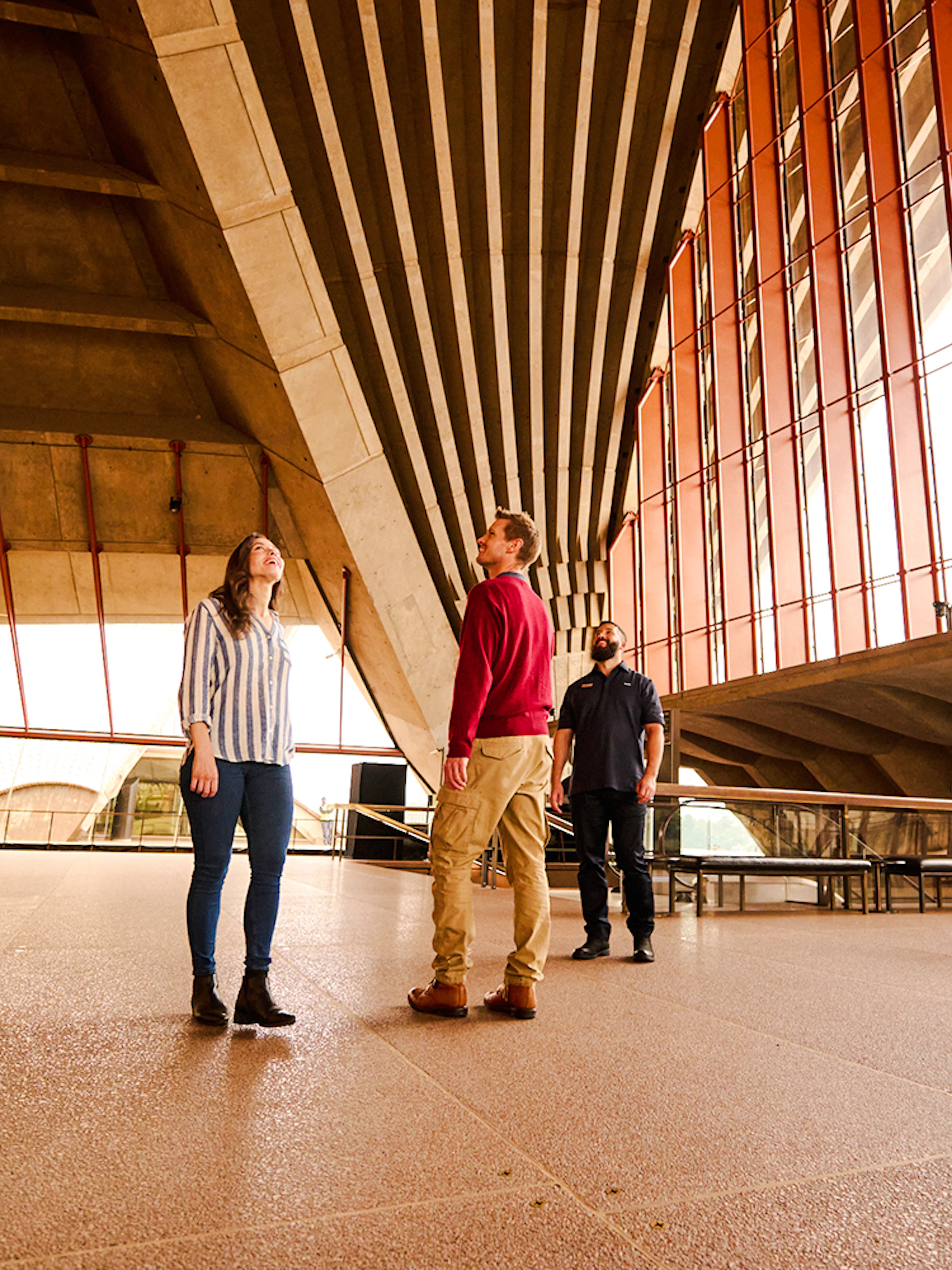 Guided tour inside Sydney Opera House with people observing architecture.