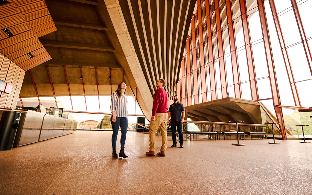 Guided tour inside Sydney Opera House with people observing architecture.