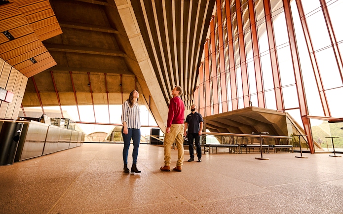 Guided tour inside Sydney Opera House with people observing architecture.