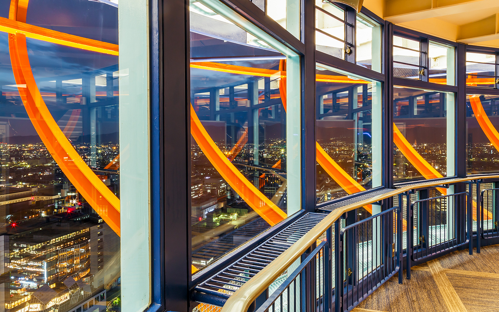 Kyoto Tower observation deck illuminated at night with city view.