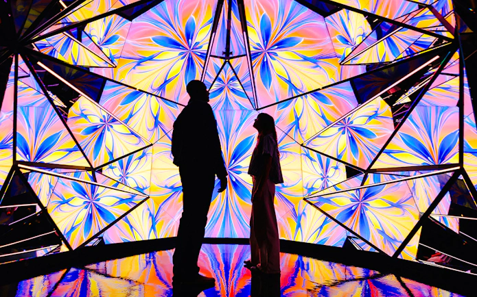 Silhouettes of two people at Edge NYC Observation Deck with colorful kaleidoscopic background.