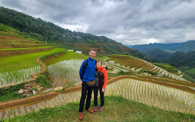 Couple standing by terraced rice fields in Mu Cang Chai during trekking and motorbike tour.