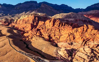 Red Rock Canyon's vibrant cliffs and winding road, view from helicopter tour, Las Vegas.