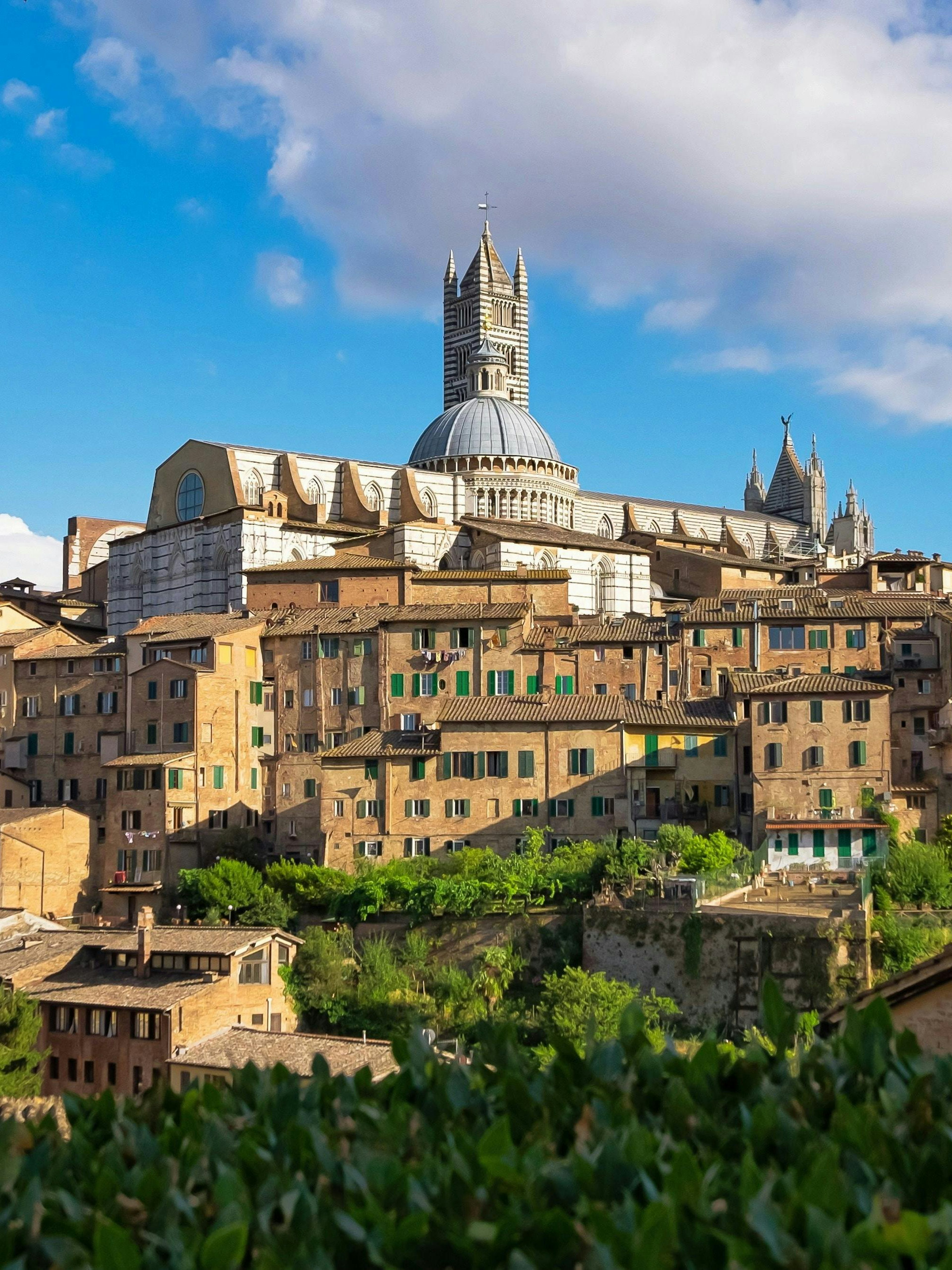 Siena Cathedral rising above the medieval hilltop town of Siena, Tuscany, Italy.
