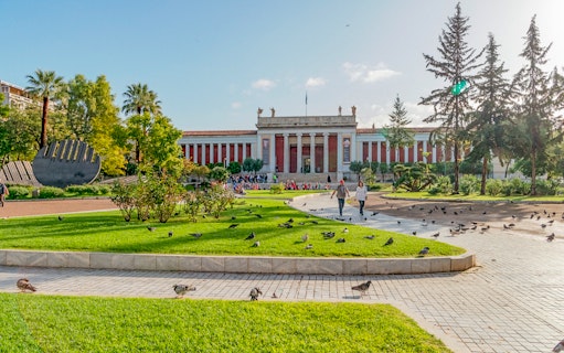 National Archaeological Museum facade with gardens and visitors in Athens.