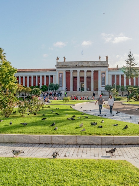 National Archaeological Museum facade with gardens and visitors in Athens.