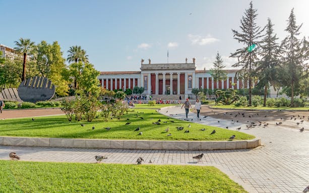 National Archaeological Museum facade with gardens and visitors in Athens.