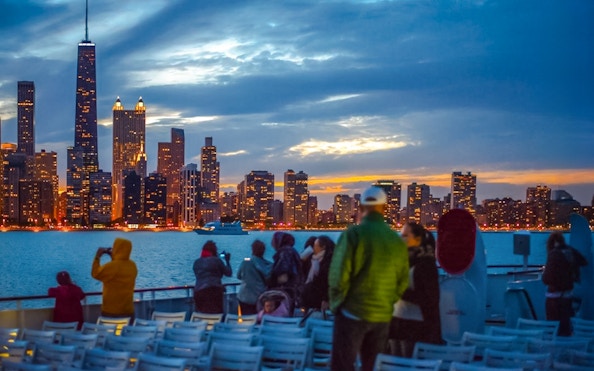Cruise passengers view Chicago skyline at sunset on Lake Michigan.