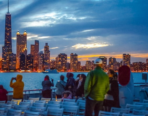 Cruise passengers view Chicago skyline at sunset on Lake Michigan.