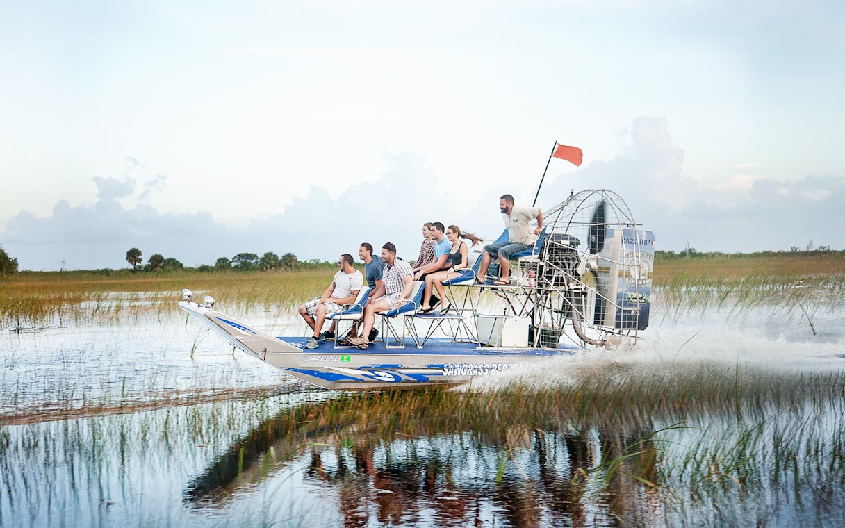 Airboat gliding through Everglades at Sawgrass Recreation Park with passengers.