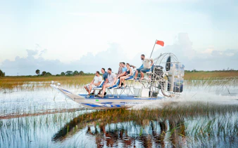 Airboat gliding through Everglades at Sawgrass Recreation Park with passengers.