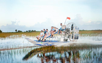 Airboat gliding through Everglades at Sawgrass Recreation Park with passengers.