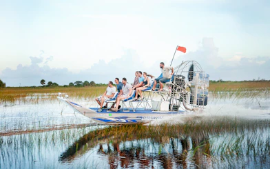 Airboat gliding through Everglades at Sawgrass Recreation Park with passengers.