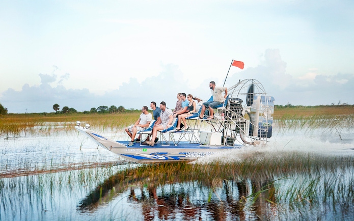 Airboat gliding through Everglades at Sawgrass Recreation Park with passengers.