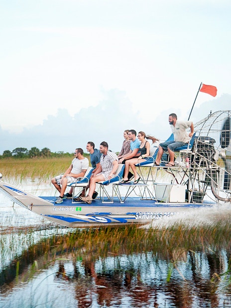 Airboat gliding through Everglades at Sawgrass Recreation Park with passengers.
