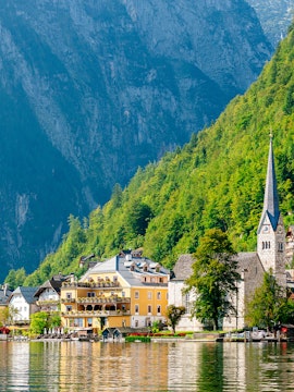 Colorful buildings and church by Hallstatt Lake, Austria, with mountains in the background.