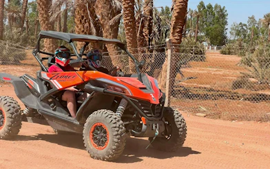 Buggy ride through palm oasis in Marrakech with two people wearing helmets.