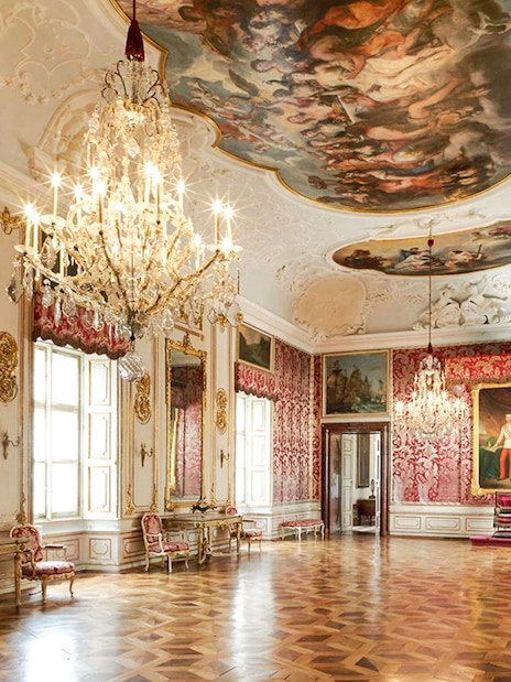 Elegant room in Salzburg's Mirabell Palace with chandeliers and ornate decor.