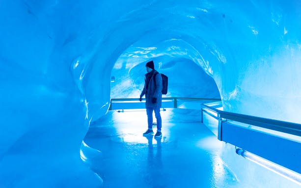Person exploring glacier cave in Titlis, Switzerland.