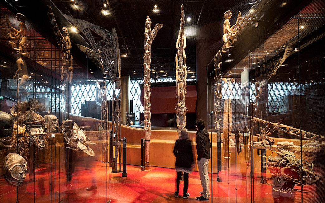 Quai Branly Museum interior with visitors viewing indigenous art displays, Paris.