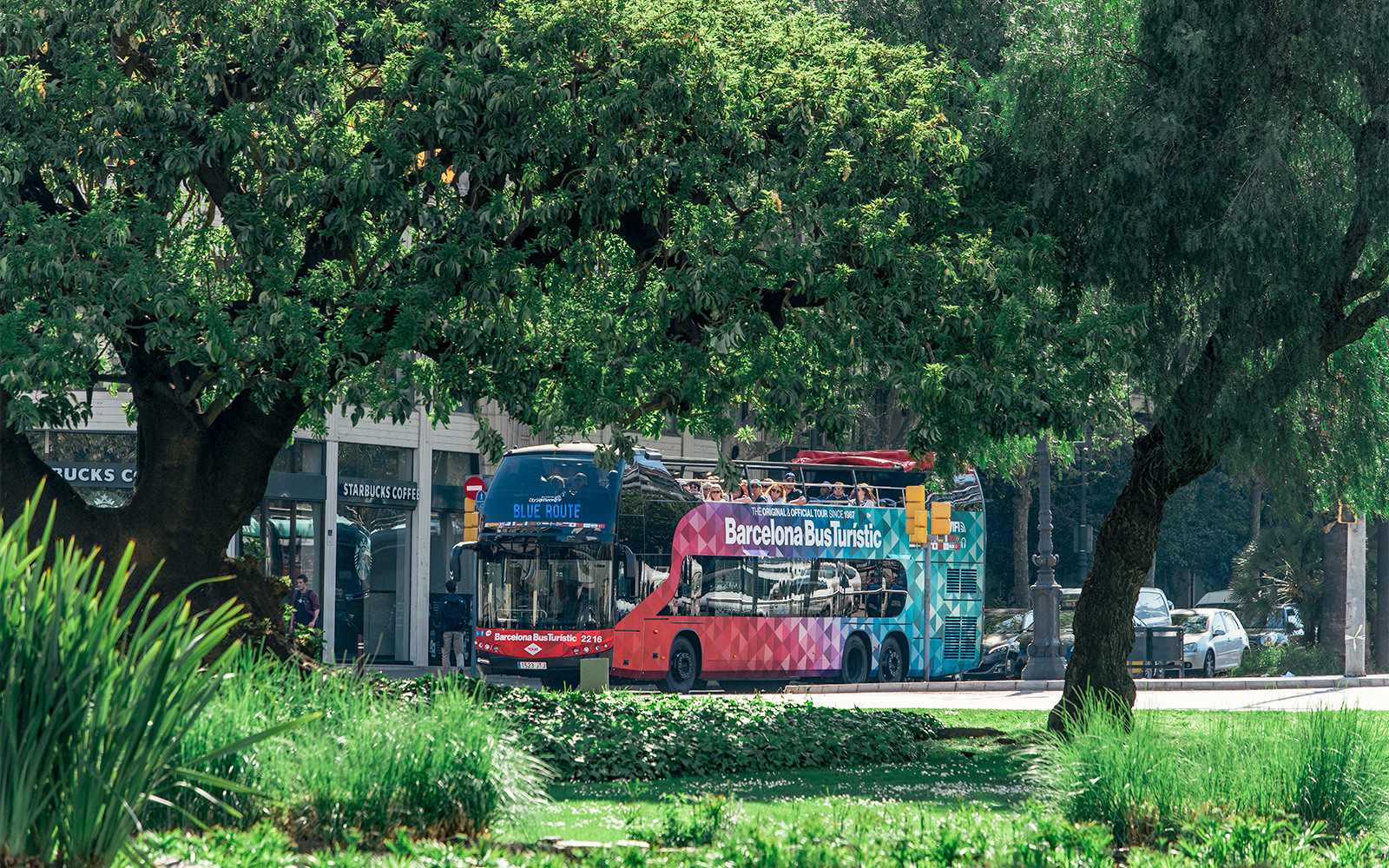 Barcelona Bus Turistic on a city street surrounded by trees.