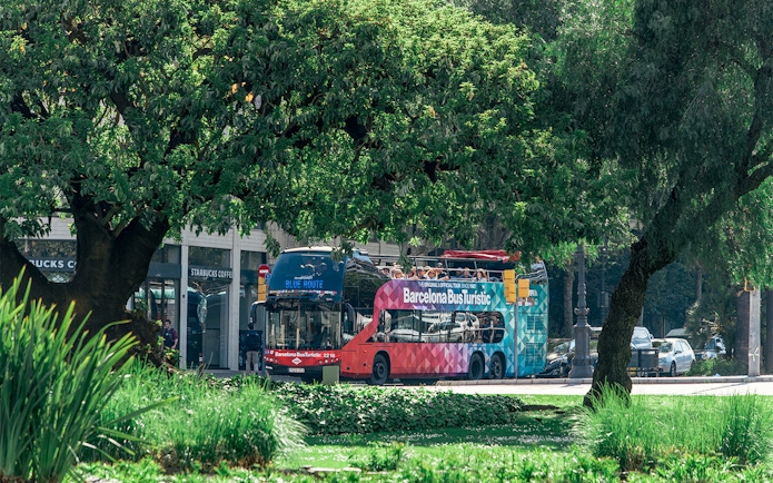 Barcelona Bus Turistic on a city street surrounded by trees.
