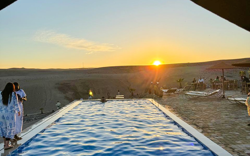 Infinity pool overlooking Agafay desert at sunset, Marrakesh camping experience.