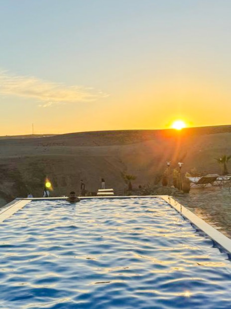 Infinity pool overlooking Agafay desert at sunset, Marrakesh camping experience.