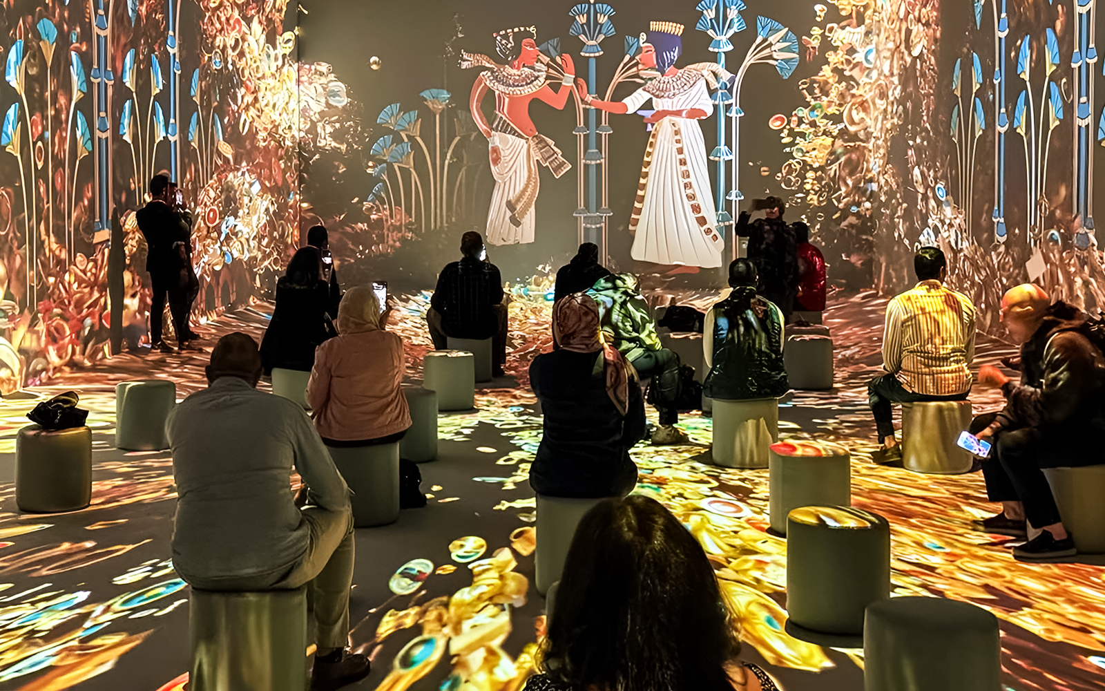 Visitors seated, watching an interactive digital exhibition with ancient Egyptian themes.