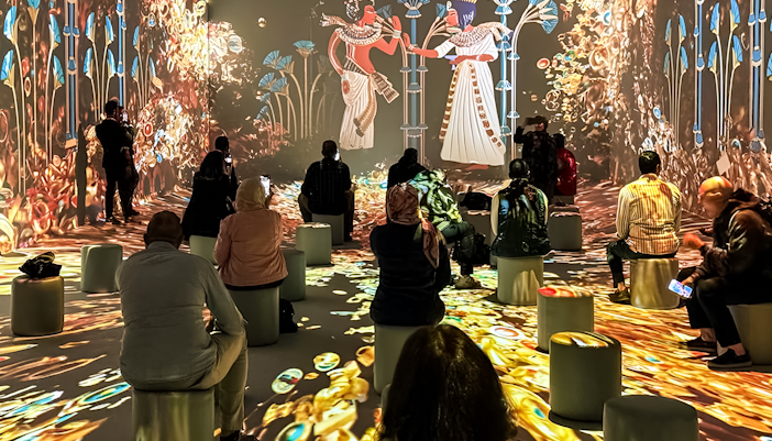 Visitors seated, watching an interactive digital exhibition with ancient Egyptian themes.