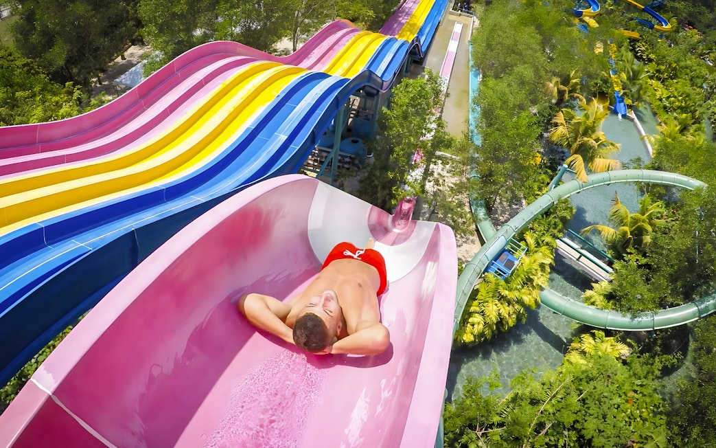 Man sliding down a colorful water slide at Escape Penang water park.
