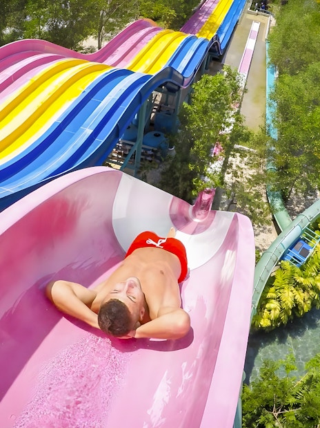 Man sliding down a colorful water slide at Escape Penang water park.