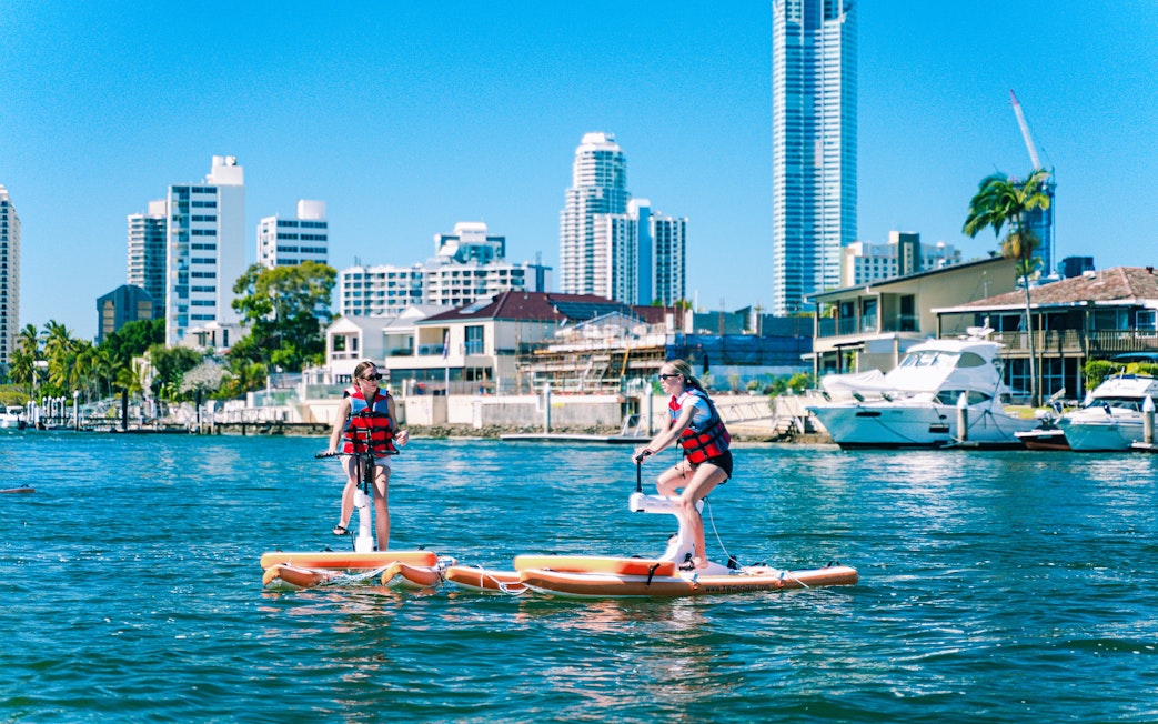 Tourists riding waterbikes on the Gold Coast with city skyline in the background.