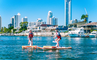 Tourists riding waterbikes on the Gold Coast with city skyline in the background.