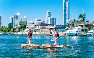 Tourists riding waterbikes on the Gold Coast with city skyline in the background.