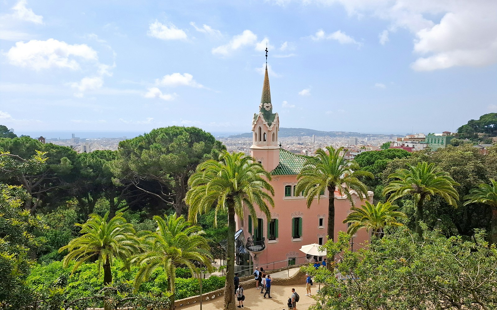 Gaudí House Museum in Park Güell, Barcelona, surrounded by palm trees and cityscape.