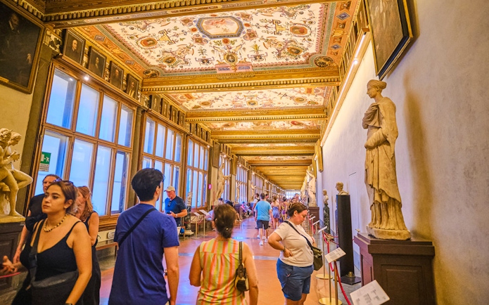 Visitors exploring the ornate Vasari Corridor in the Uffizi Gallery, Florence.