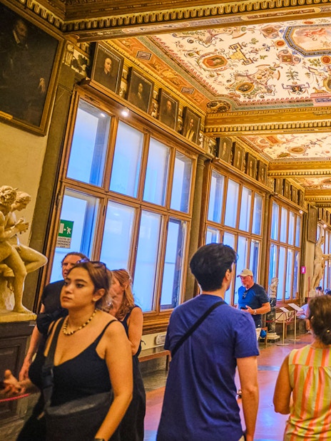 Visitors exploring the ornate Vasari Corridor in the Uffizi Gallery, Florence.