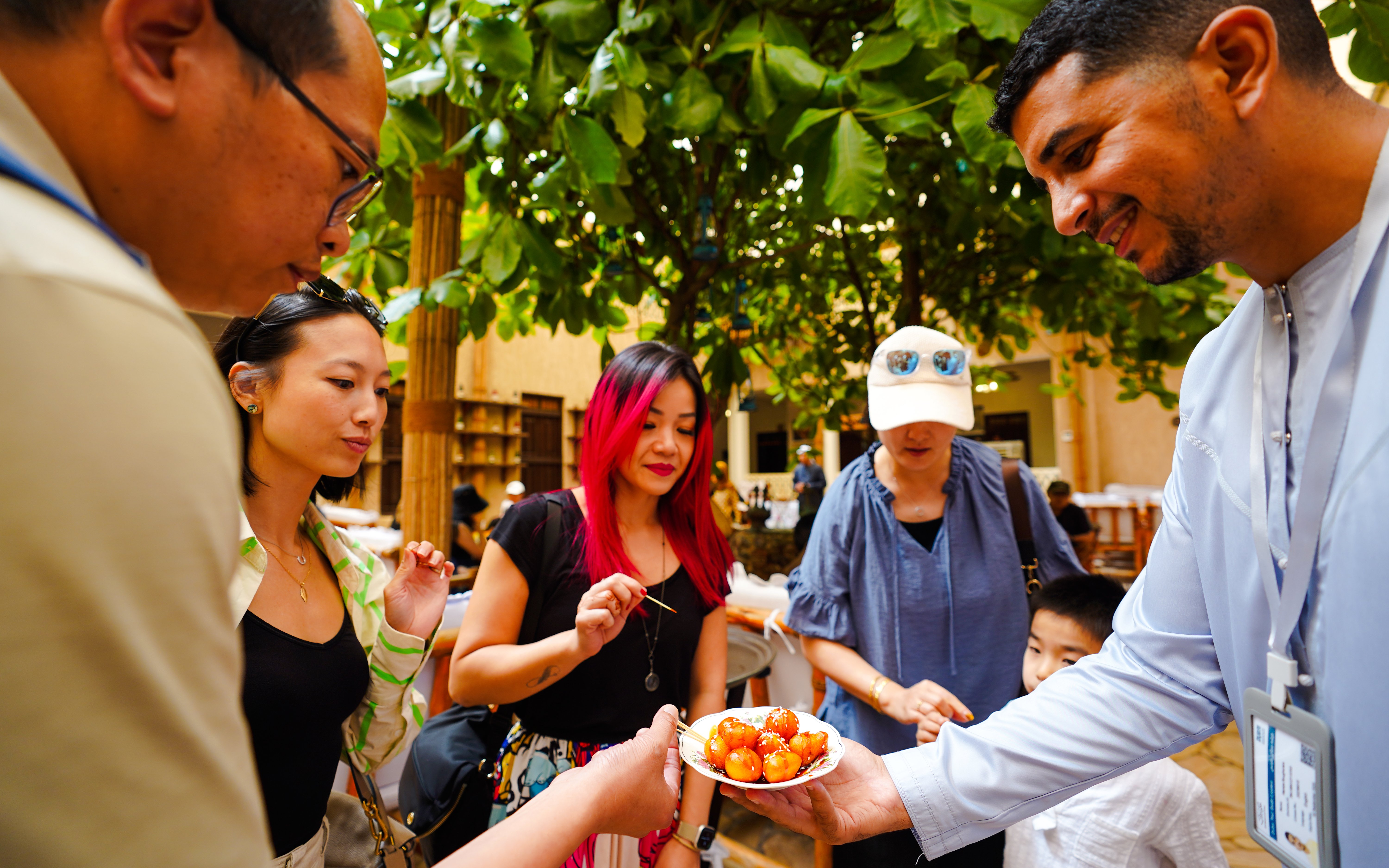 Visitors sampling street food at an outdoor market.