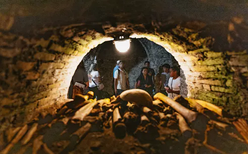 Visitors exploring Roman catacombs with ancient bones in foreground.