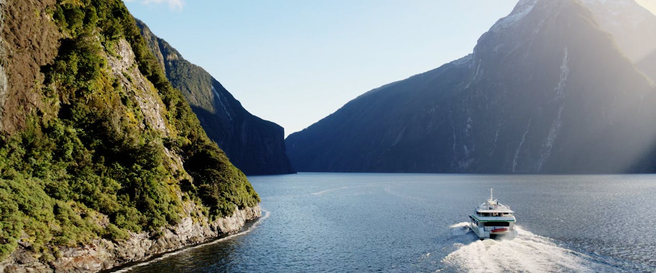 Milford Sound fjord with cascading waterfalls and lush cliffs, New Zealand.