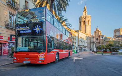 Valencia hop-on hop-off bus near Palma de Mallorca stop with historic buildings in view.