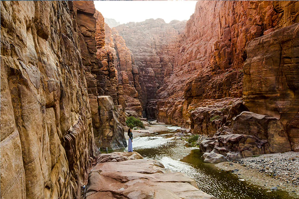 Hiker on Wadi Mujib Siq Trail surrounded by canyon walls, Amman.