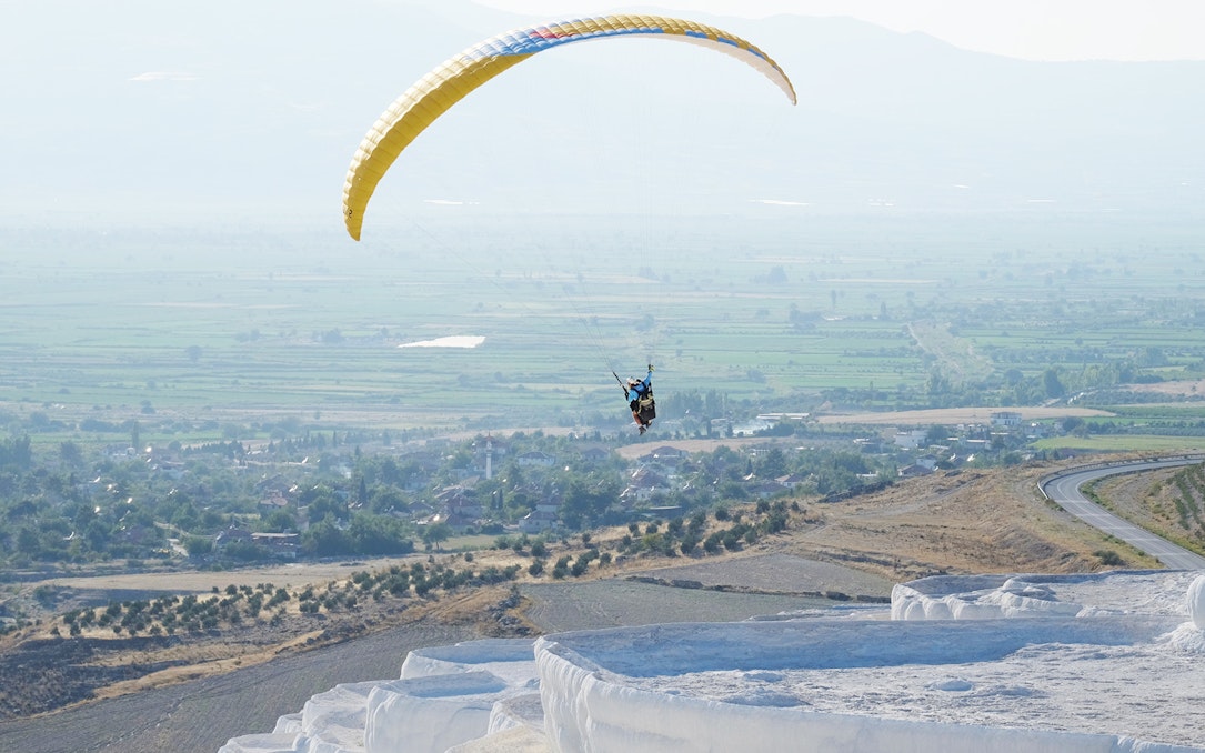 Tandem paragliding over Pamukkale's travertine terraces, Turkey.