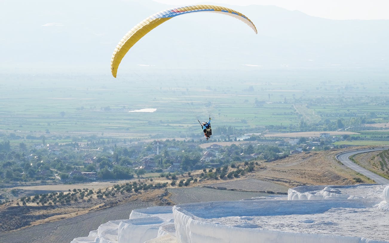 Tandem paragliding over Pamukkale's travertine terraces, Turkey.